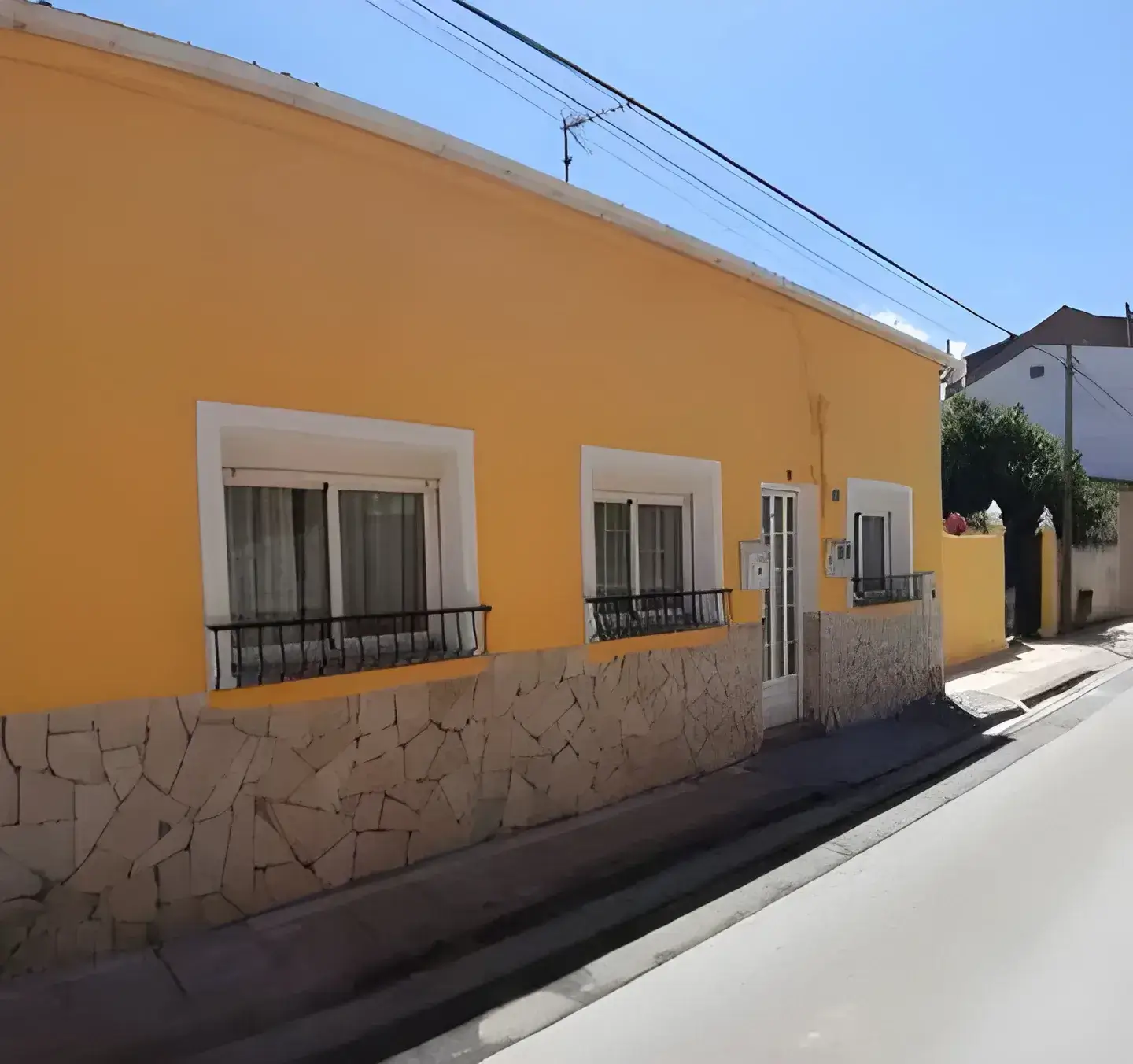 Los Pintores Guadalajara Fachada de casa tradicional pintada en color amarillo con zócalo de piedra
